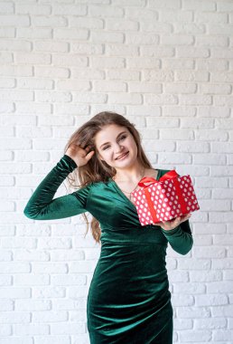 Yeşil elbiseli genç ve güzel bir kadın. Elinde hediye kutusu var.