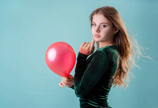 穿着绿色衣服的性感女人拿着蓝色背景的红色气球 — 图库照片