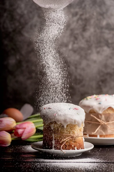 Zuckerpuder auf glasiertem Osterkuchen auf dunklem rustikalem Hintergrund — Stockfoto