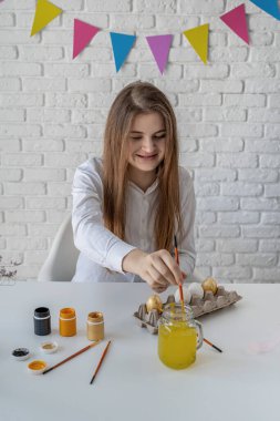 Paskalya için yumurta boyayan gülümseyen genç kadın.
