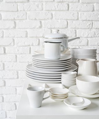 Beyaz seramik çanak yığınları ve masa örtüsü beyaz tuğla duvar zemininde fotokopi alanı ile masa örtüsü