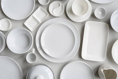 piles of white ceramic dishes and tableware top view on gray background clipart