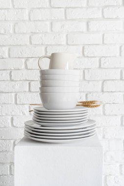 stack of white ceramic dishes and tableware on white brick wall background