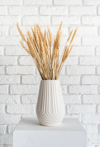 Wheat spikes in a white vase on white brick wall background — Stockfoto