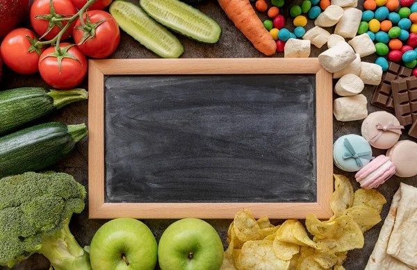 健康的で不健康な食品の概念 果物と野菜対お菓子とポテトフライ空白のチョークボードの周りトップビューフラットレイ — ストック写真