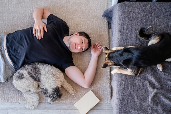 Joven tirado en el suelo en casa con sus perros — Foto de Stock