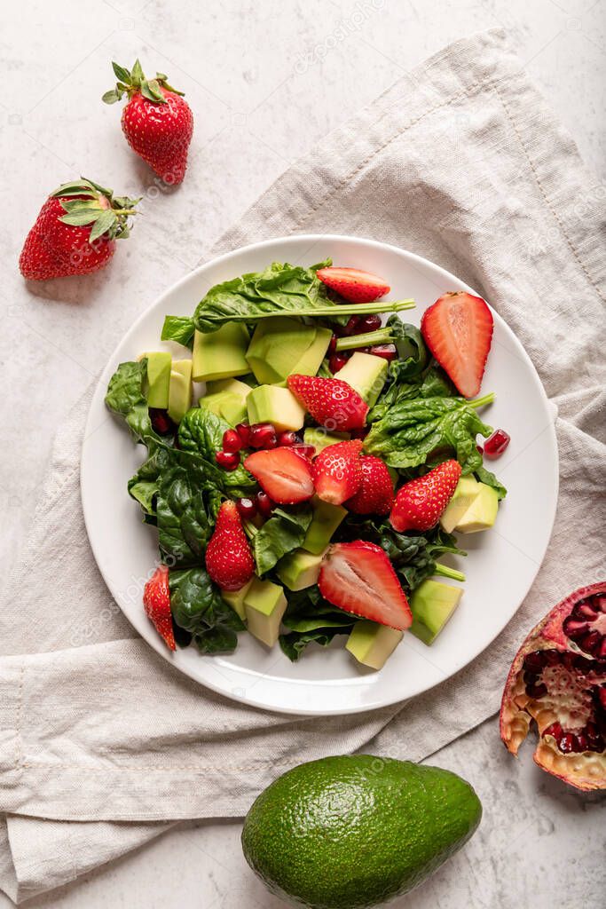 Healthy dieting. Fresh salad with strawberries, avocado and spinach top view flat lay on white background