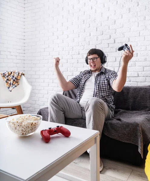Podekscytowany młody człowiek gra w gry wideo w domu ciesząc się zwycięstwem — Zdjęcie stockowe