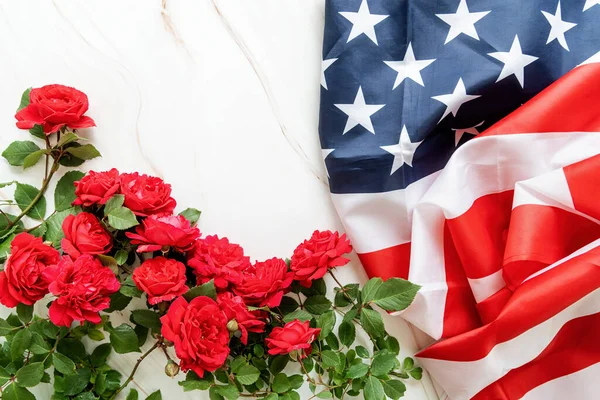 Independence Day USA concept. Memorial Day. Red roses over the USA flag top view flat lay with copy space