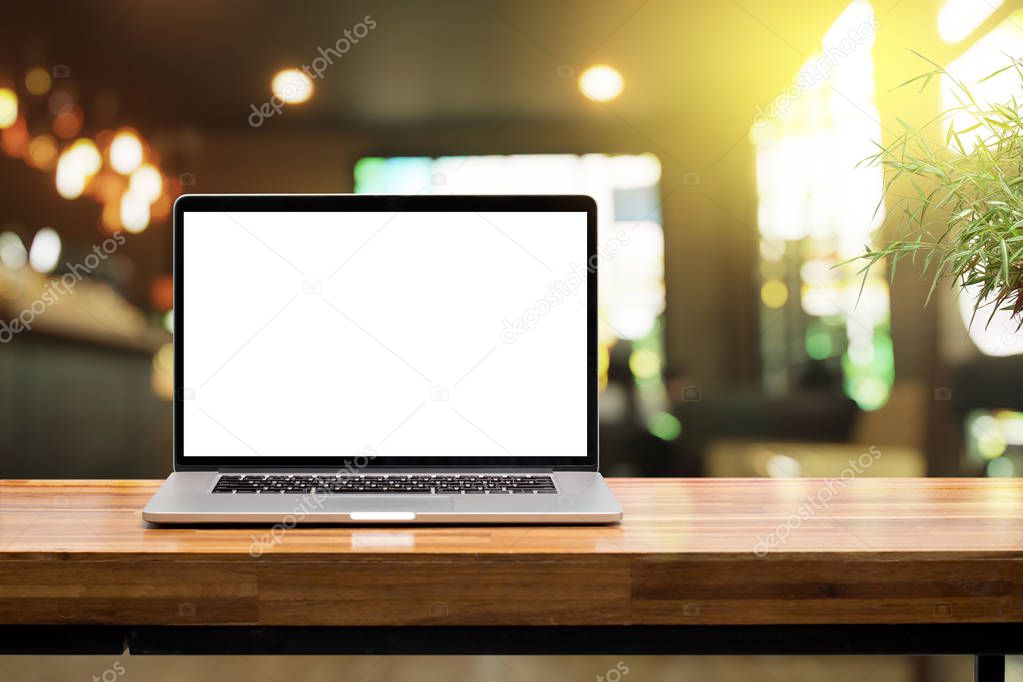 Laptop blank screen on wooden table in coffee shop morning sunshine