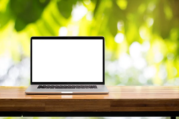 Pusty ekran laptopa na drewnianym stole w zielonym ogrodzie niewyraźne tło — Zdjęcie stockowe