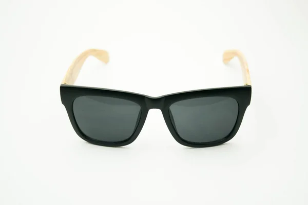 Чорні сонцезахисні окуляри з дерев'яними ногами на білому тлі — стокове фото