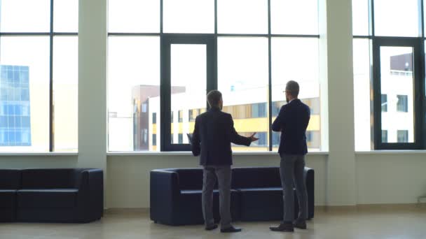 Dos hombres de negocios cerca de la ventana para discutir los términos del contrato — Vídeo de stock