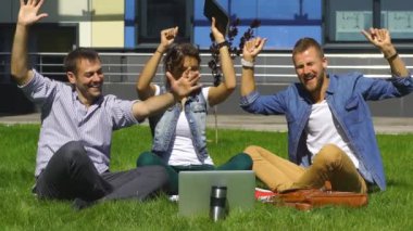 çim ve şarkı üzerinde oturan mutlu öğrenciler