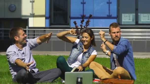 Glada studenter sitta på gräsmattan och sjunga — Stockvideo