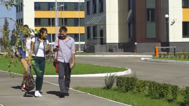 Drie studenten in het park, op hun weg naar college, makend pret op een helder — Stockvideo