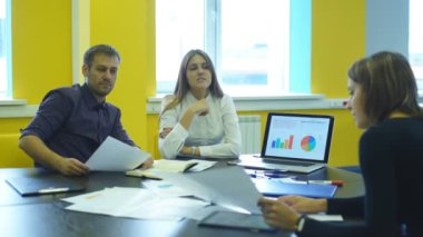 Ofiste oturan iki kadın ve bir işadamı ve iş planı tartışmak