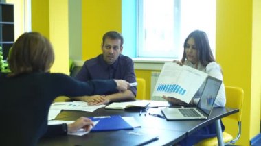 üç iş arkadaşı ofiste oturan klasörlerde belgelere bakarak iletişim
