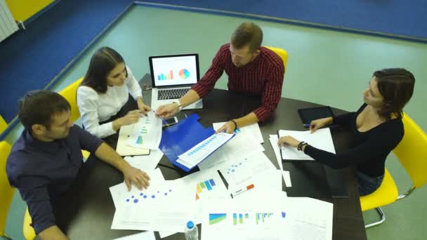 Mensen uit het bedrijfsleven het schrijven van een marketing plan en analyse Grafiekpapier op houten tafel, met computer laptop — Stockvideo