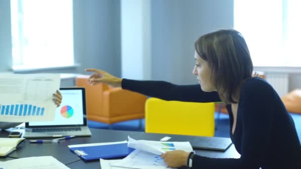 Две женщины и бизнесмен сидят в офисе и обсуждают бизнес-план — стоковое видео