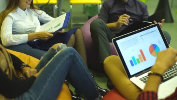 Четыре студента с ноутбуком на диване, в кампусе — стоковое видео