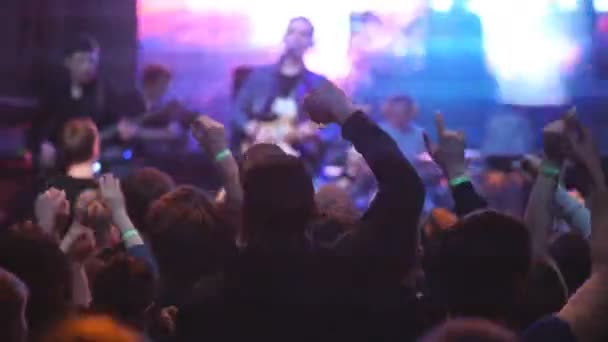 Тольятти, Россия, 23 апреля 2016 года: аудитория с поднятыми руками на музыкальном фестивале и огнями, струящимися сверху сцены. Софт-фокус, высокий ISO — стоковое видео