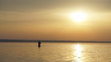 Gün doğumu bir denizde su adam