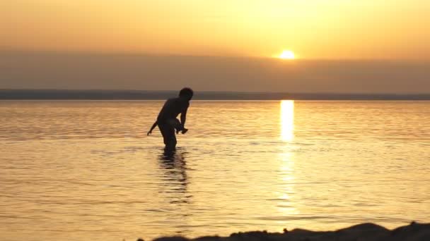 Far och son leker på stranden vid solnedgången — Stockvideo