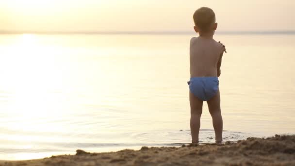 Silhouet van kind op het strand, die zijn handen omhoog, knuffelen de zon — Stockvideo