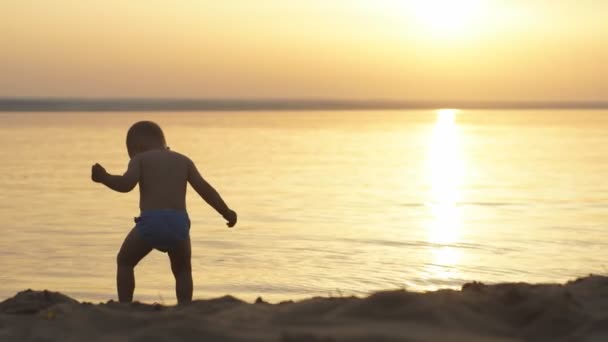 Маленький хлопчик на пляжі на заході сонця — стокове відео