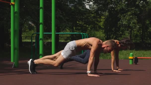 Hombre y mujer haciendo ejercicio en el parque de la ciudad. Hermosa joven pareja multirracial — Vídeos de Stock