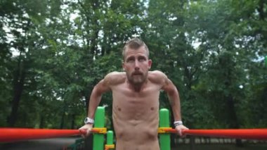 Eğitim ve yaşam tarzı kavramı - karın yapan genç erkek egzersiz paralel Bar yaz Park üzerinde