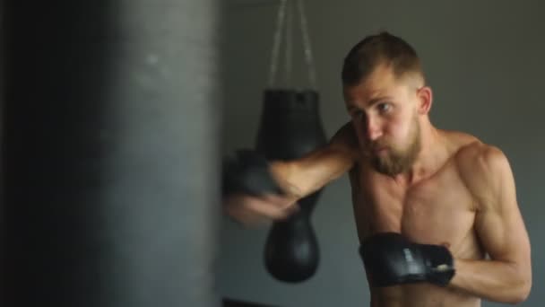 Hombre atlético joven haciendo ejercicio con un saco de boxeo pesado — Vídeos de Stock