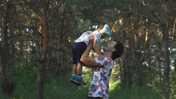 Отец бросает своего маленького сына в воздух медленно — стоковое видео