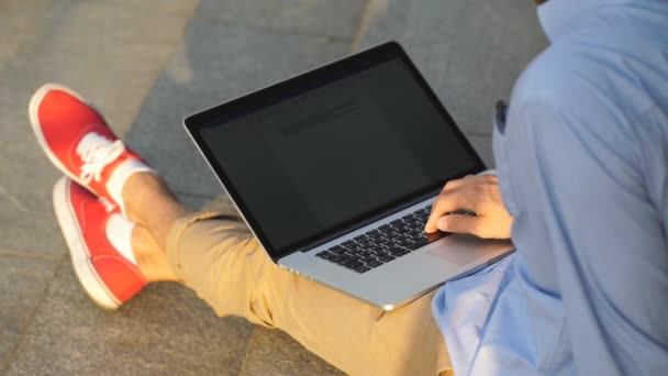 Современный бизнесмен-хипстер сидит на лестнице и пользуется ноутбуком — стоковое видео