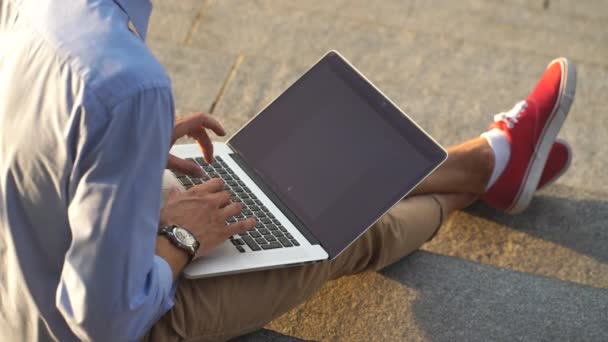 Homem de negócios moderno hipster sentado nas escadas e usando laptop — Vídeo de Stock