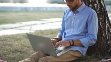 Yakışıklı hipster dizüstü Park'ta bir yaz gününde kullanma.
