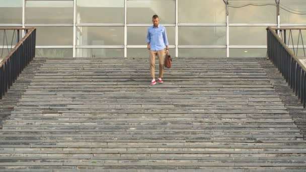 Un jeune homme descend les escaliers et regarde sa montre — Video