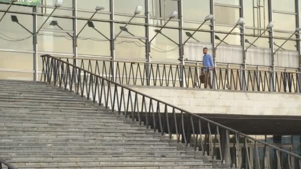 Um jovem desce as escadas e olha para o relógio — Vídeo de Stock