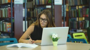 Kütüphanede bir bilgisayarda çalışan kız öğrenci