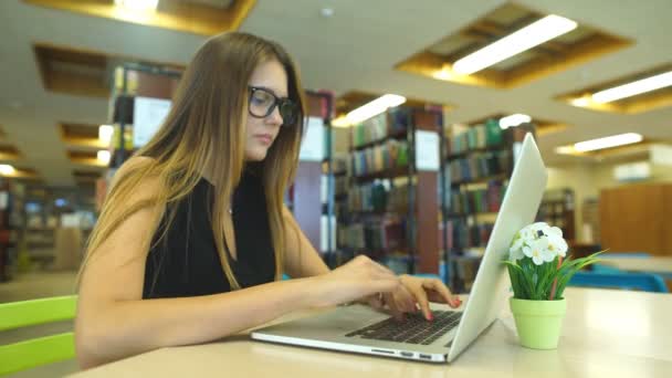 Красивая студентка в библиотеке университета — стоковое видео