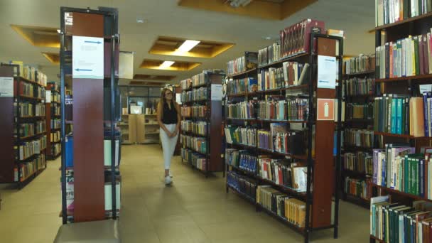 Studentin spaziert in der Bibliothek der Universität — Stockvideo