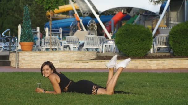 Piękna dziewczyna, leżąc na trawie i śmiejąc się — Wideo stockowe