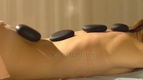 Молода жінка отримує гарячий кам'яний масаж в спа-салоні — стокове відео