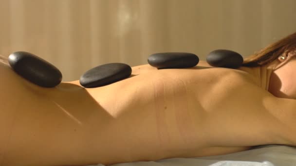 Junge Frau bekommt heiße Steinmassage im Wellness-Salon — Stockvideo