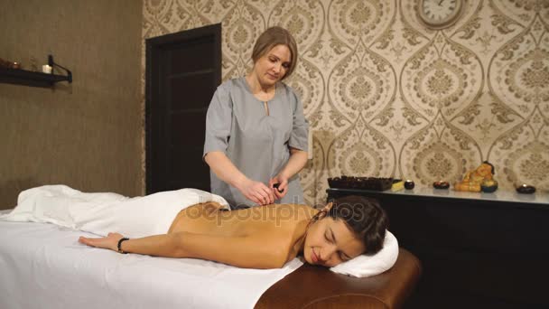 Девушка на каменной терапии, массаж горячими камнями — стоковое видео