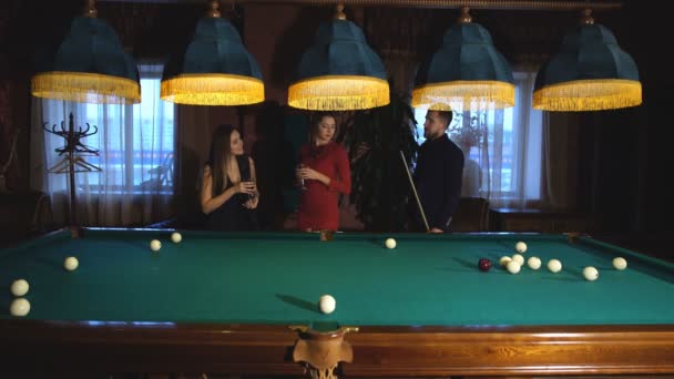 Un homme joue au billard et deux jeunes belles femmes regardent le jeu — Video