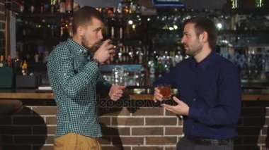 tezgahta konuşan iki genç adam. iki arkadaş ayakta bar ve viski içme