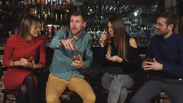 Компания из двух пар отдыхает в баре и пьет — стоковое видео