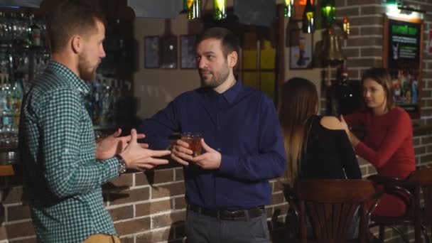 Zwei junge Männer unterhalten sich am Schalter. zwei Freunde stehen in der Bar und trinken Whisky — Stockvideo